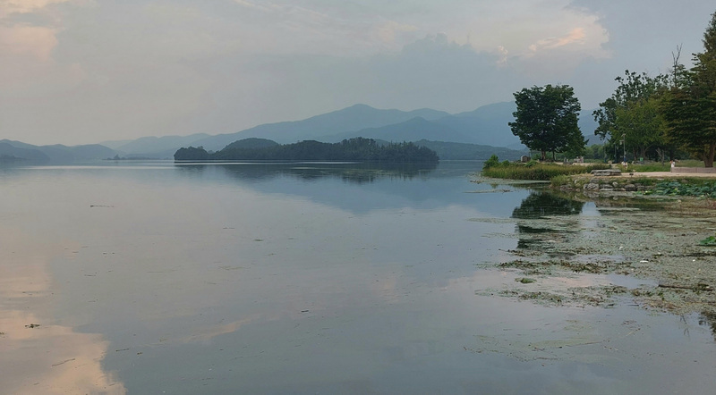 A misty river at sunset with mountains behind fading into the distance