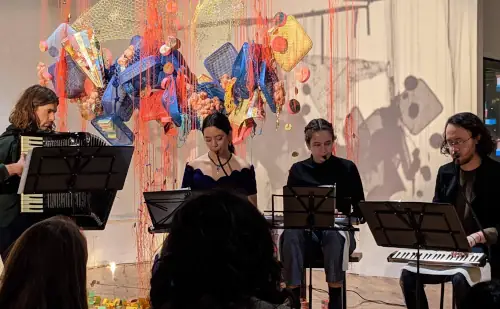 Four people playing melodicas and accordions at a concert.
